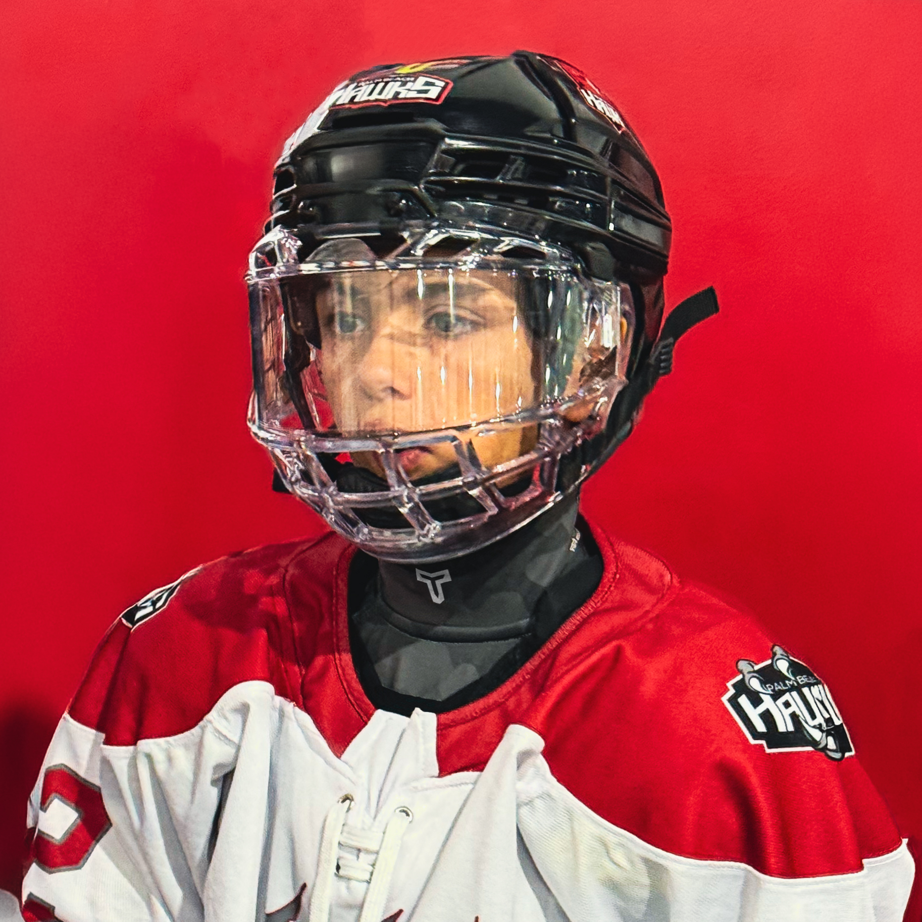 Person wearing a hockey cut resistant shirt and helmet with a red background